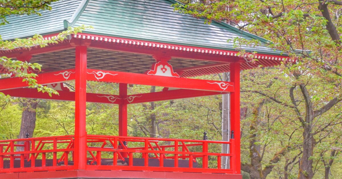 鮮やかな赤色の屋根付き舞台が公園内に建つ風景