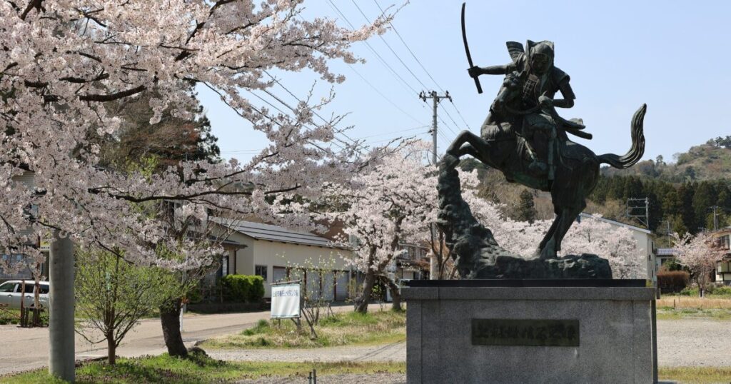 桜の中に立つ上杉謙信の騎馬像
