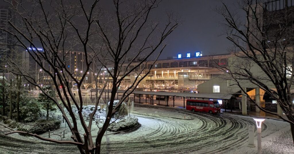 雪の夜にライトアップされた新潟駅とロータリー