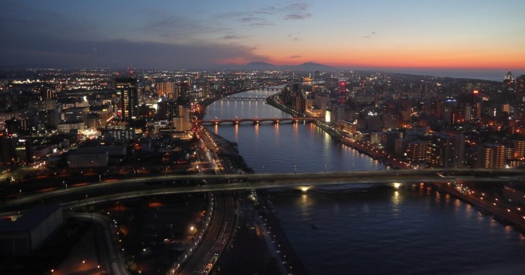 夕暮れに染まる信濃川と萬代橋、ライトアップされた新潟市街の夜景