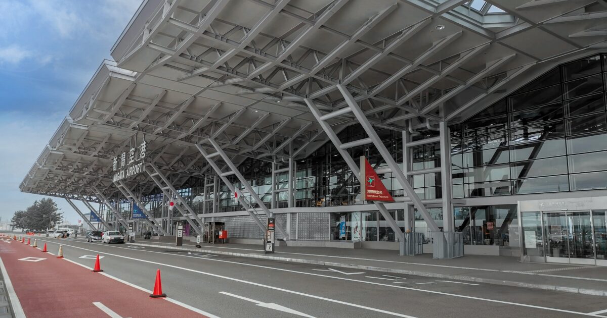 新潟空港のモダンな外観と送迎車両が並ぶ出発エリア