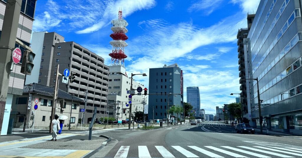 青空の下で新潟市内を走る幹線道路と赤白の電波塔