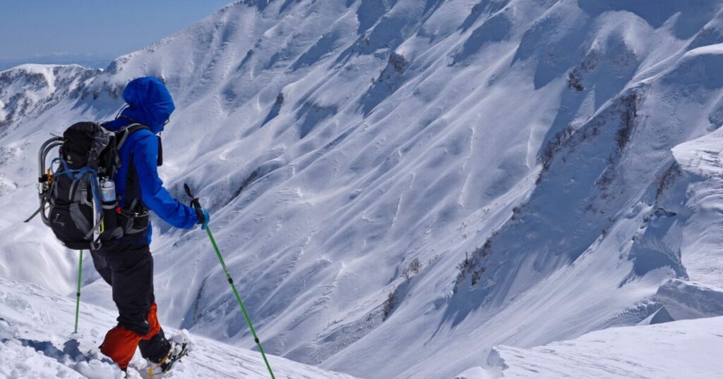雪山で登山する登山者と厳冬の山岳風景