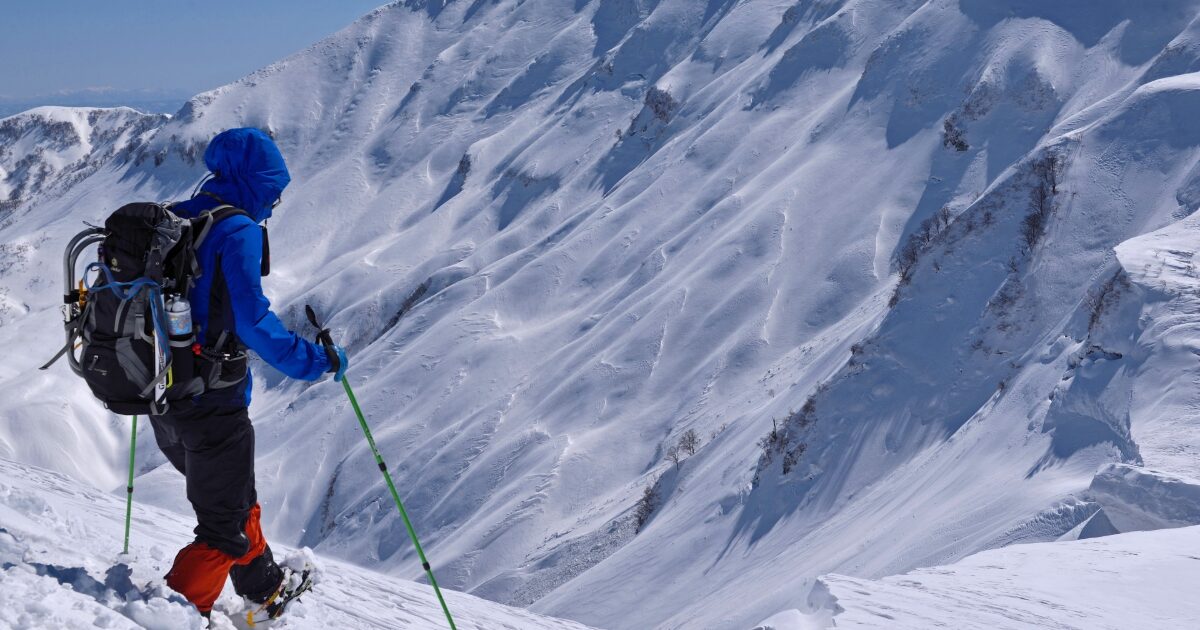 雪山で登山する登山者と厳冬の山岳風景