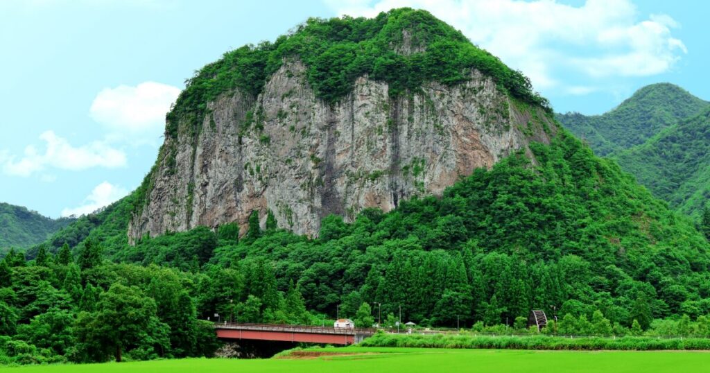 夏の緑に囲まれた大迫力の岩山と田園風景