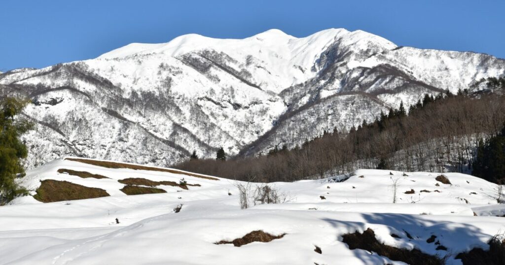 雪に覆われた山里と雄大な白銀の山々の風景