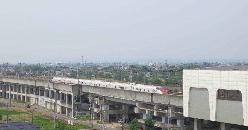 高架を走る新幹線と駅のある郊外の風景