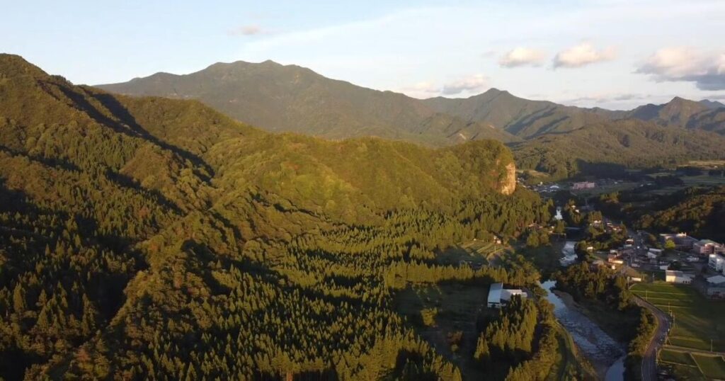 山々と川に囲まれた日本の田舎の町並みと自然風景の空撮
