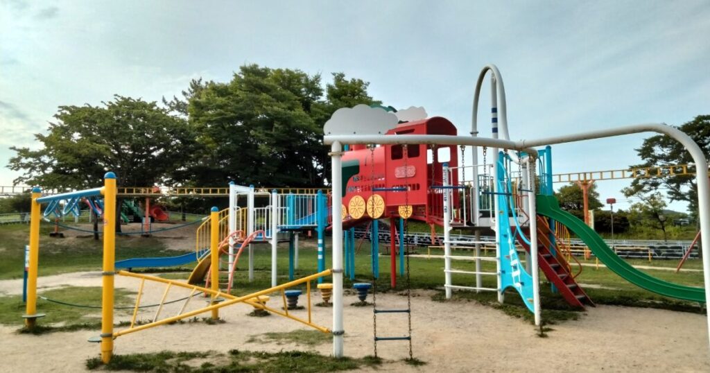 すべり台や遊具が並ぶカラフルな公園の遊び場