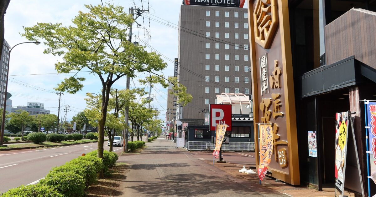 アパホテルと街路樹が並ぶ都市の歩道